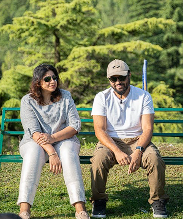 A couple resting together on a bench amid pine trees